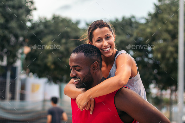 Young man piggybacking his friend after doing sports