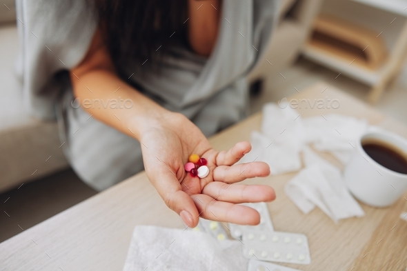 A woman with a cold with pills is treated at home chooses which drugs to take and self-medicates