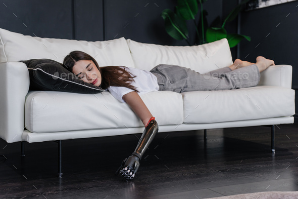 girl with artificial mechanical hand sleeps on couch after workout. Rehabilitation after trauma