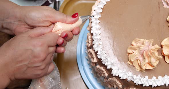 Confectioner Woman is Pouring Cream on Sponge Cake Using Pastry Bag Closeup View alt