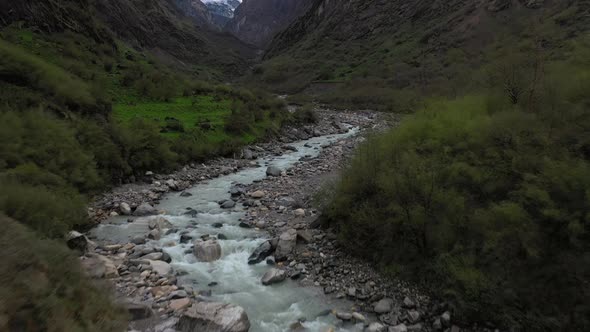Revealing aerial drone shot of a white water river and a large mountain side in the Annapurna mounta alt