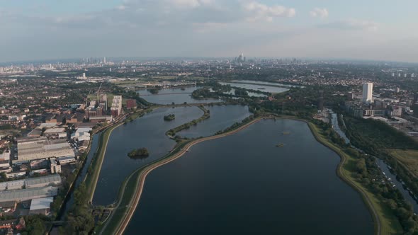Dolly forward drone shot over north London water reservoirs Walthamstow towards city skyline alt