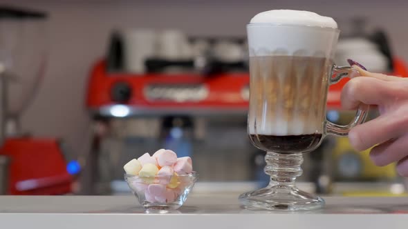 Waiter Putting Coffee Next to the Marshmallows on a Bar alt