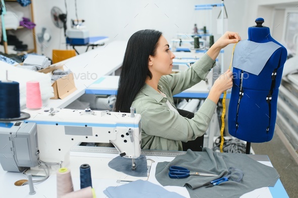 Professional dressmaker woman sews clothes on sewing machine at