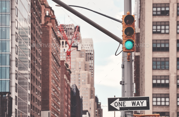 One Way road sign and traffic lights in New York City, color toning applied, selective focus, USA.