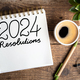 2024 New year resolutions on desk. 2024 goals list with notebook, coffee cup, plant on wooden backgr - PhotoDune Item for Sale