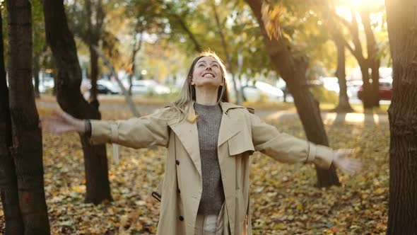 Happy Woman Throwing Leaves in Autumn in Slow Motion Smiling alt