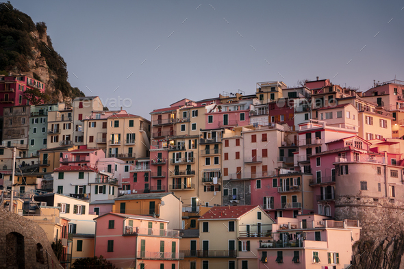 Picturesque row of houses in varying shades of pink perched atop a steep hillside in a quaint town