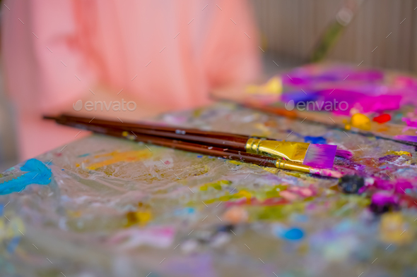 Close-up of girl artist taking paint brushes from a table during an art lesson concept of art