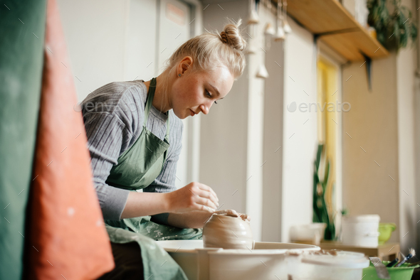 Woman potter moulding walls of clay ware on potters wheel - Stock Photo - Images