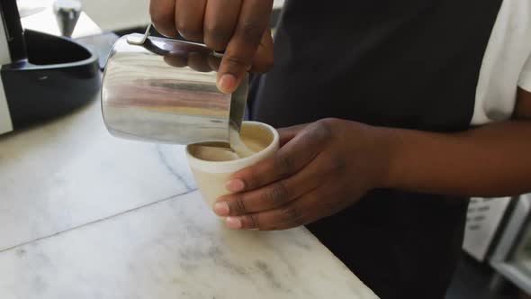 Close up of african american male barista making coffee at cafe alt