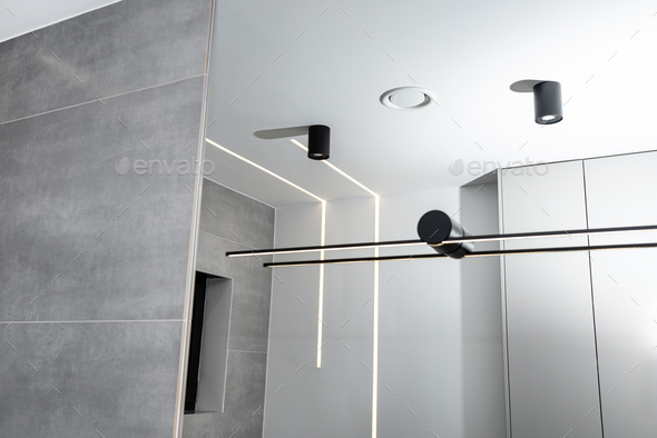 LED light strips mounted in the wall and ceiling in a modern bathroom, visible ventilation anemostat