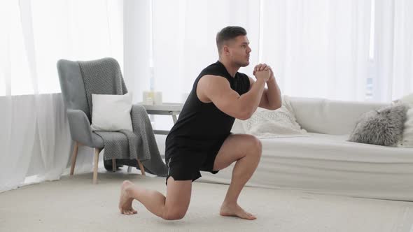 Sporty Young Man Is Doing Lunge Squat Exercise in Jump in Living Room at Home.