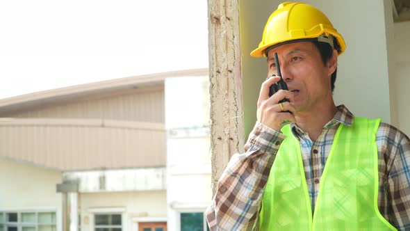 Asian engineer or Architect put on a helmet for safety and use walkie talkie for a talk with a contr alt