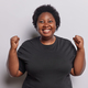 Excited cheerful obese dark skinned woman with curly hair dressed in casual black tshirt clenches - PhotoDune Item for Sale