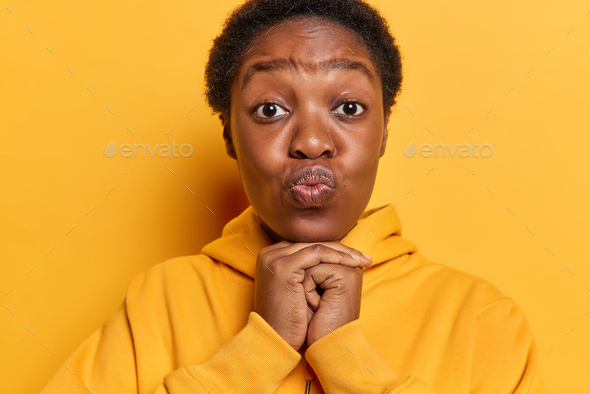 Photo of lovely dark skinned woman with short hair keeps lips folded ...