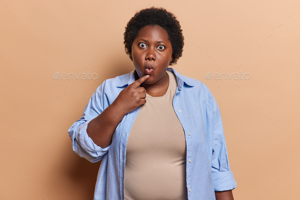 Waist up shot of stunned chubby dark skinned young African woman stares ...