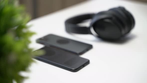 close up video of two dark smartphone and headphones on a white table alt
