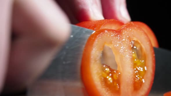 Close up view of cutting fresh tomato by kitchen knife. Soft focus.