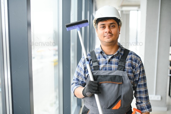 Male professional cleaning service worker cleans the windows and shop windows