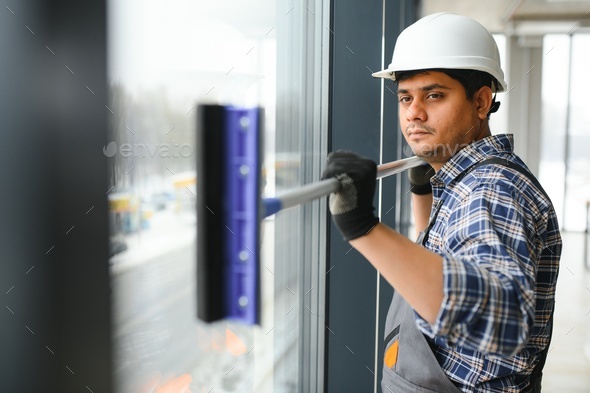 Male professional cleaning service worker cleans the windows and shop windows