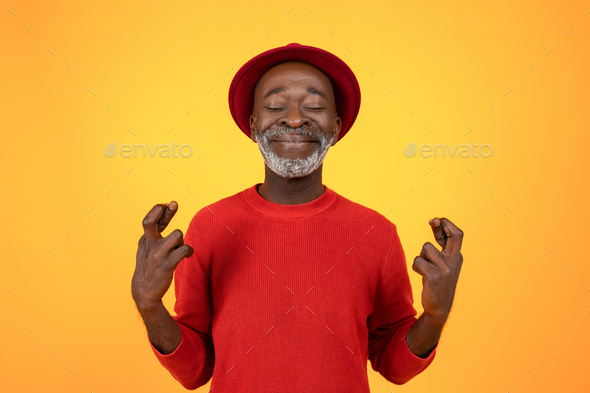 Smiling old black man in hat and red clothes, with closed eyes, crossed fingers sign