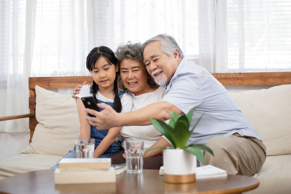 Grandparents using phone taking selfie with granddaughter