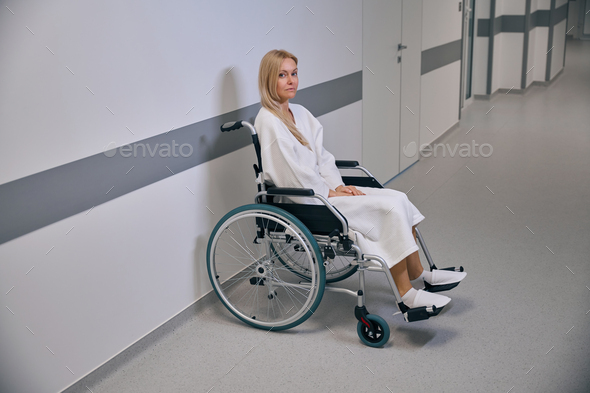 Sad disabled patient waiting for medical assistance in hospital hallway