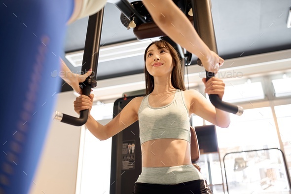 Woman training her chest muscles with a pectoral fly machine Stock Photo by  cait00sith