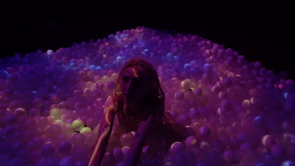Young Woman Playing with Balls in a Dry Pool Spotlight with Abstract Video Art alt