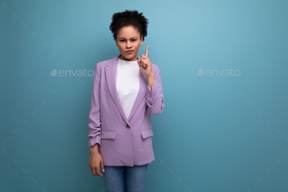 young well-groomed latin secretary woman with fluffy hair is dressed in a lilac jacket on a studio
