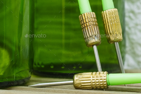 Green darts from a dartboard resting on beer bottles.