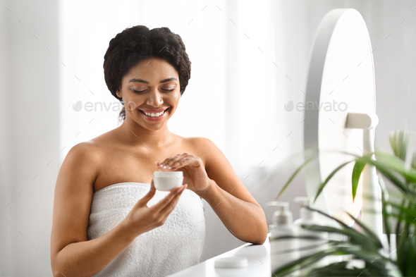 Skin Nourishing. Beautiful Smiling Black Woman Opening Jar With Face Cream