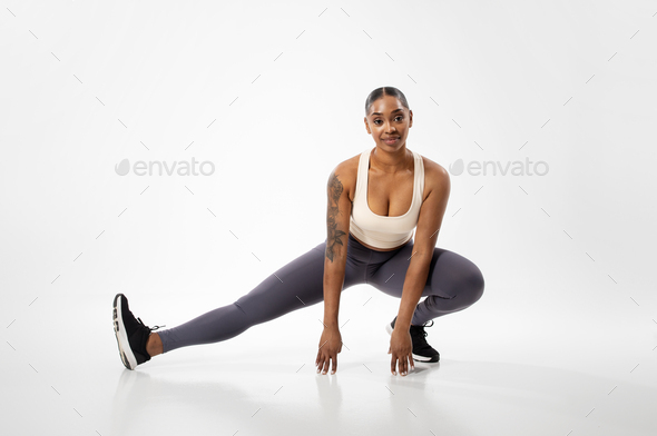 Smiling african american woman doing extreme leg stretches balancing on one  leg. Female athlete working out on flexibility exercises. stock photo