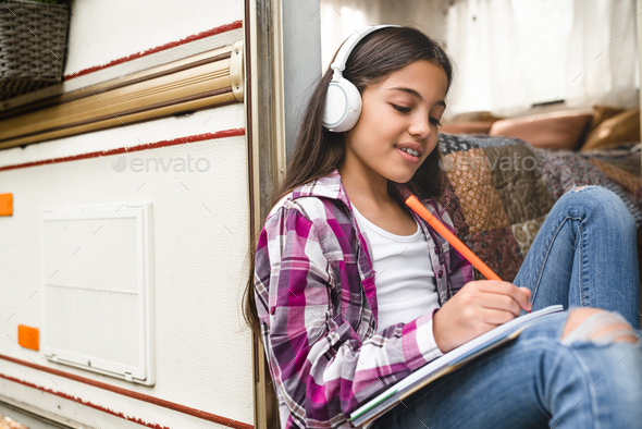 Child e-learning, listening to the music, drawing, doing homework while traveling by trailer