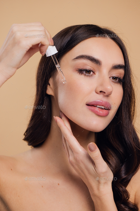 Woman Dropping Serum On Face On Beige Background Stock Photo By