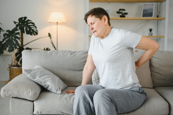 Senior adult woman touching back feeling backache, discomfort low lumbar muscular kidney pain.