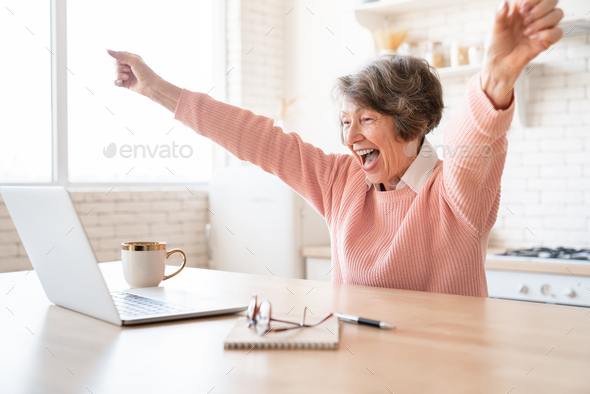 Cheerful happy overjoyed old elderly senior woman grandmother shouting celebrating winning money