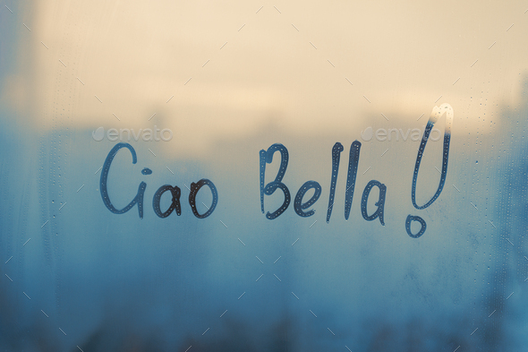 Handwritten text Ciao Bella in Italian language is Bye hi pretty in english on glass wet blue window