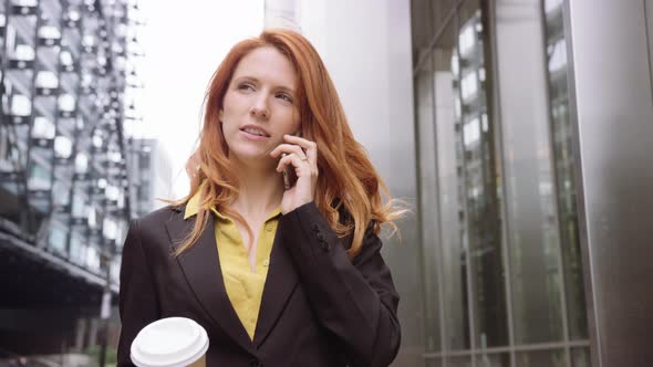 Businesswoman in city using smart phone with takeaway coffee