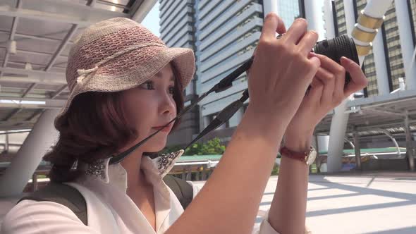 Traveler backpacker Asian woman using camera to make photo while travel at downtown in Bangkok. alt