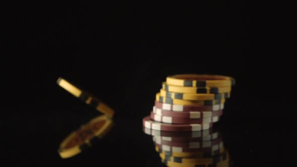 A playing chips falls on a black desk