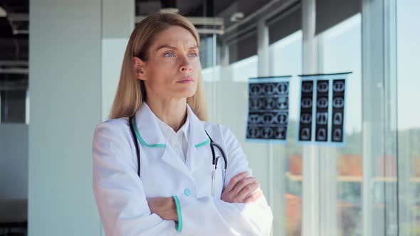 Pensive Young Female Caucasian Doctor Look in Window Folding Hands Thinking alt