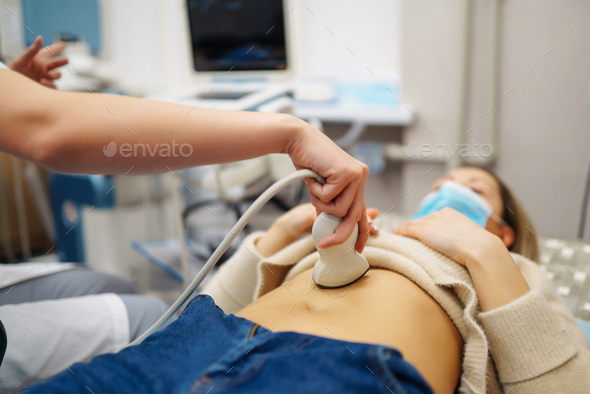 Doctor makes patient women abdominal ultrasound. Ultrasound Scanner in hands of doctor. Diagnostics.