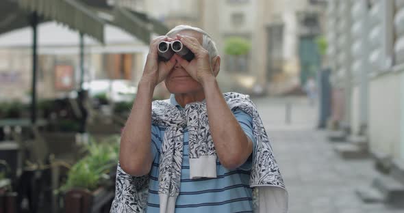 Senior Man Tourist Exploring Town, Looking in Binoculars. Travel Lviv, Ukraine alt