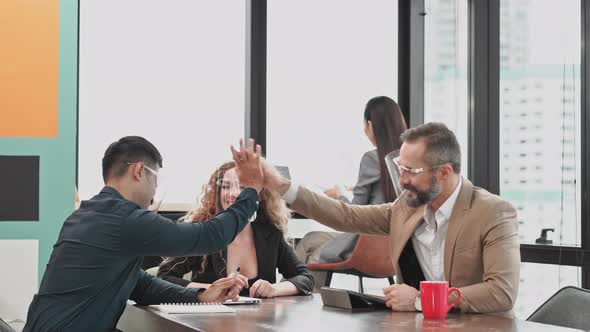 Male boss giving high five to colleagues for successful project
