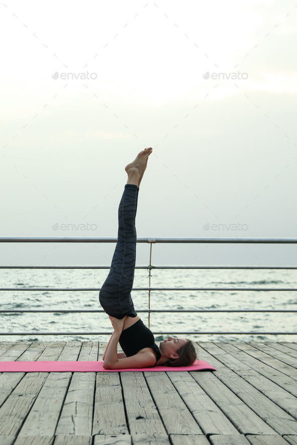 Young girl on yoga mat on wooden floor outdoors Stock Photo by