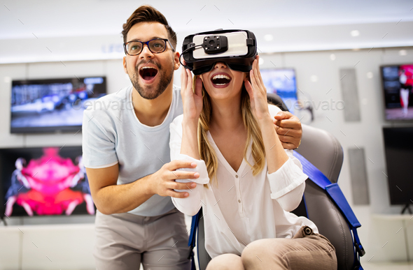 Young happy couple playing video games with virtual reality glasses in technical store