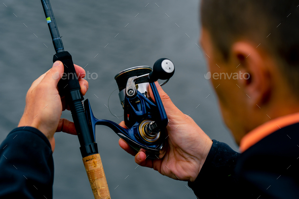 close-up Fly fisherman male hands with fishing rod spinning in hands feeder  free style method Stock Photo by guyswhoshoot