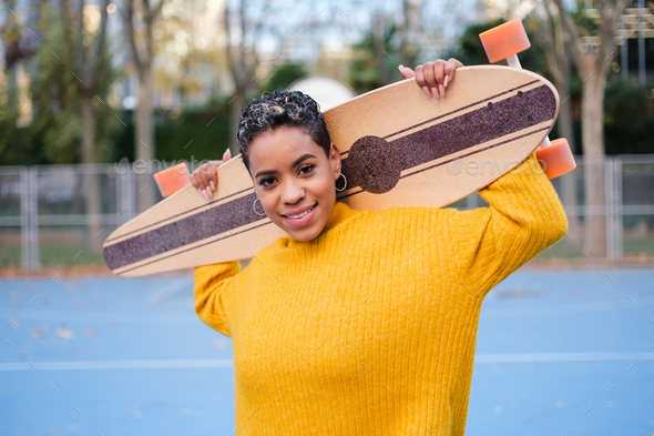 Latin young woman with short hair with skateboard in hands happy ...